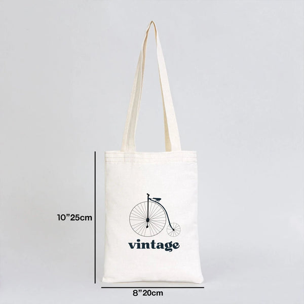 White tote bag with a vintage bicycle design and measurements on a gray background