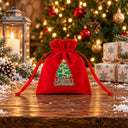 Pochette cadeau Noël en velours rouge, motif Noël à Paris tour Eiffel, sur une table rustique enneigée devant le sapin