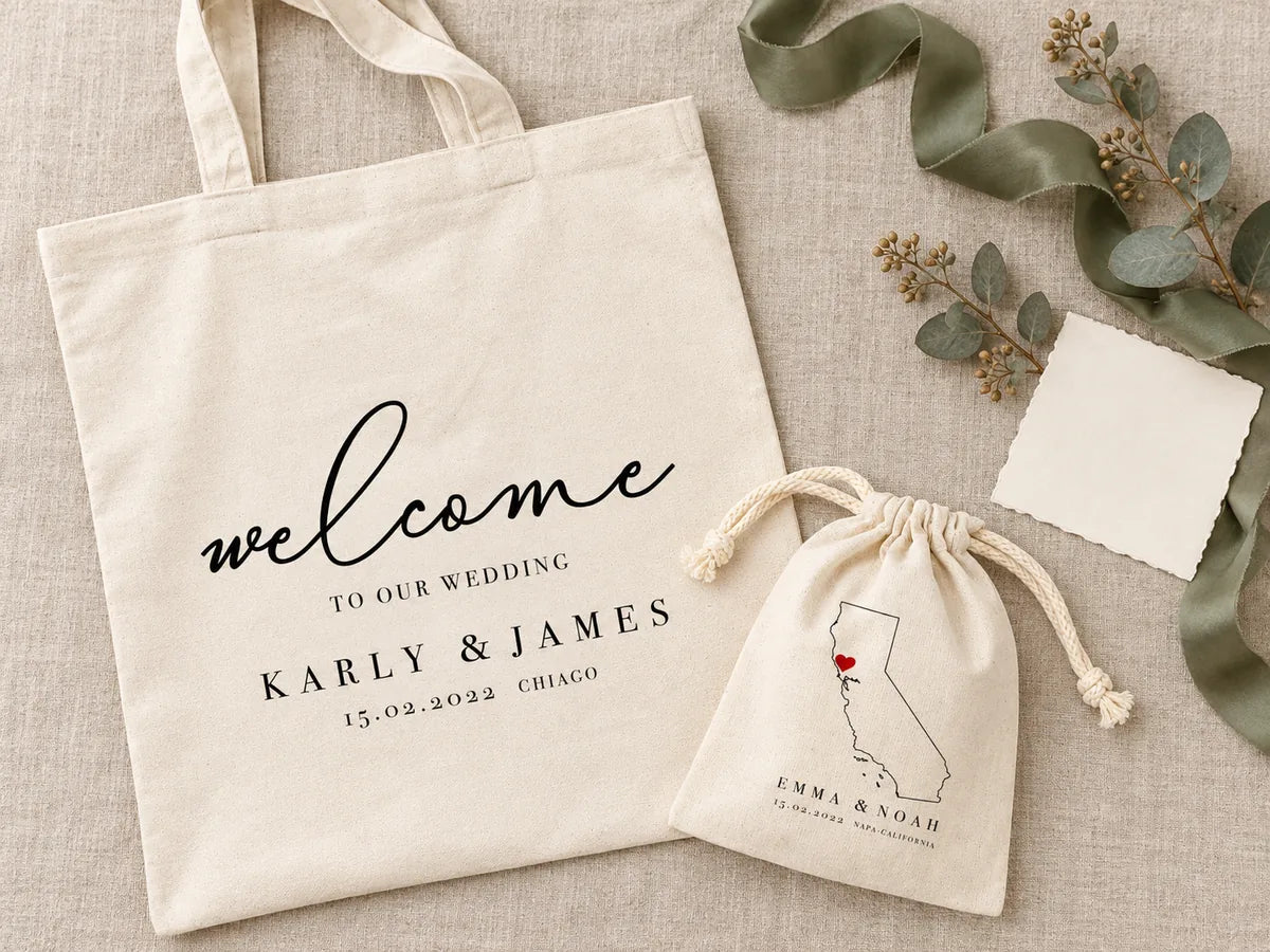 Flat-lay vu du dessus sur du lin : sac Karly & James et pochon à carte de Californie, ruban de soie vert sauge, eucalyptus séché et carte ivoire vierge